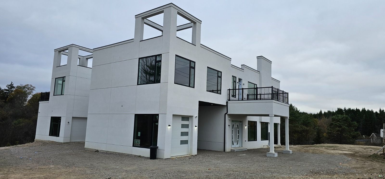 Completed modern custom home exterior by Manefa with white cladding, black railings, and large windows