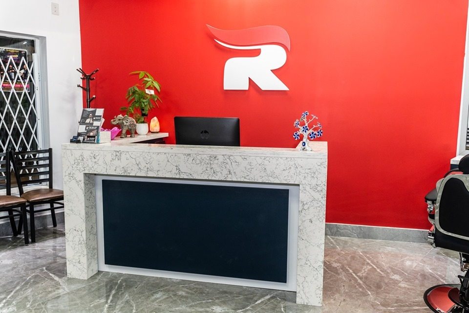Stone-look salon reception counter against a red branded feature wall