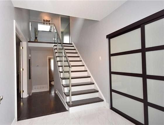 Renovated interior entry and staircase with dark wood flooring and glass railing