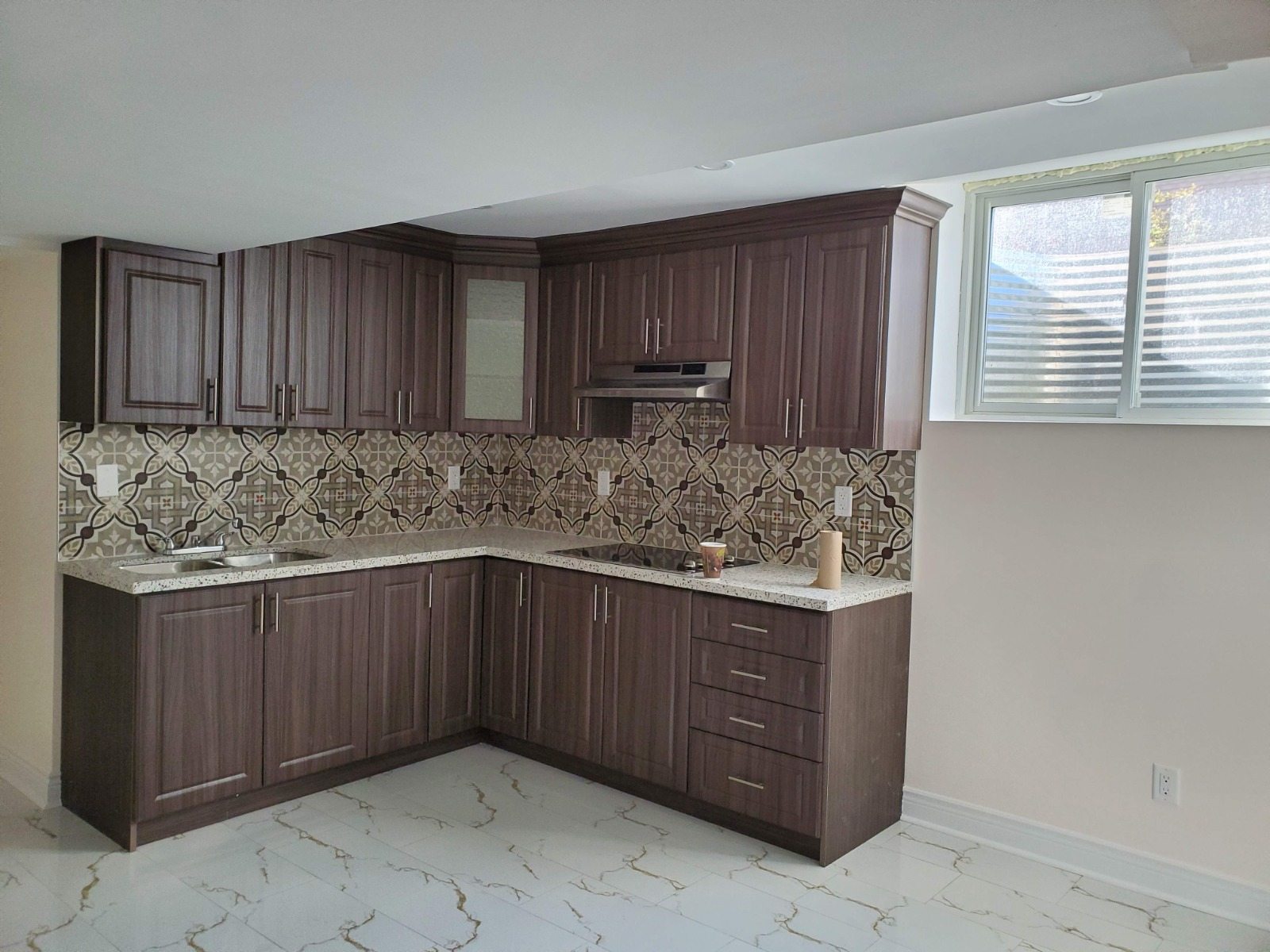 Finished basement suite kitchen with cabinetry, counters, appliances, and tile flooring