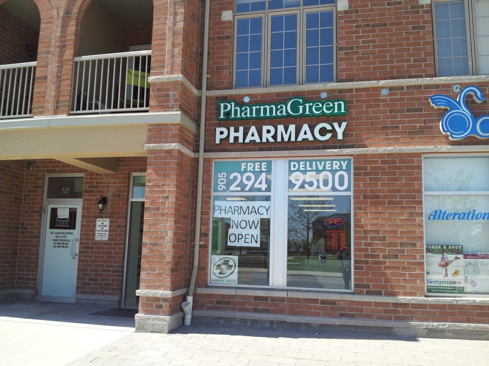 Brick pharmacy storefront with customer entrance, windows, and signage