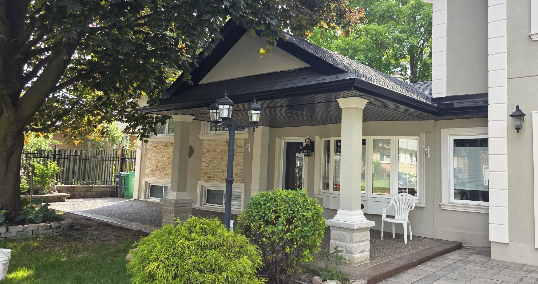 Completed covered front porch viewed from the driveway showing the finished roof, soffit, and columns