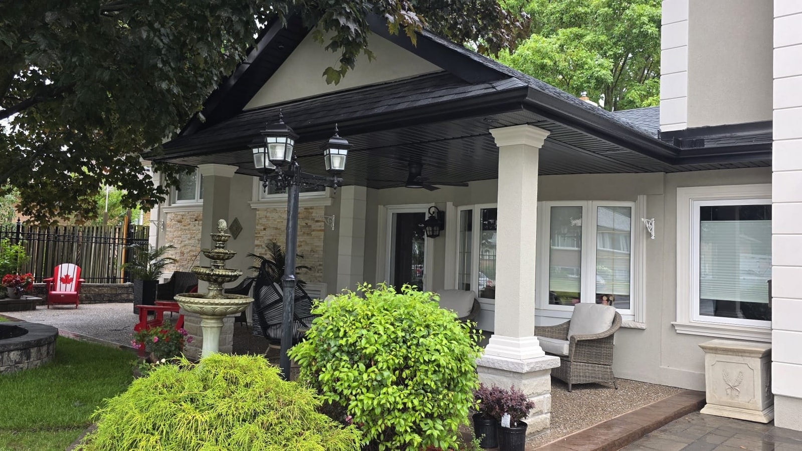 Finished covered front porch with dark shingle roof, finished columns, ceiling fan, and outdoor seating