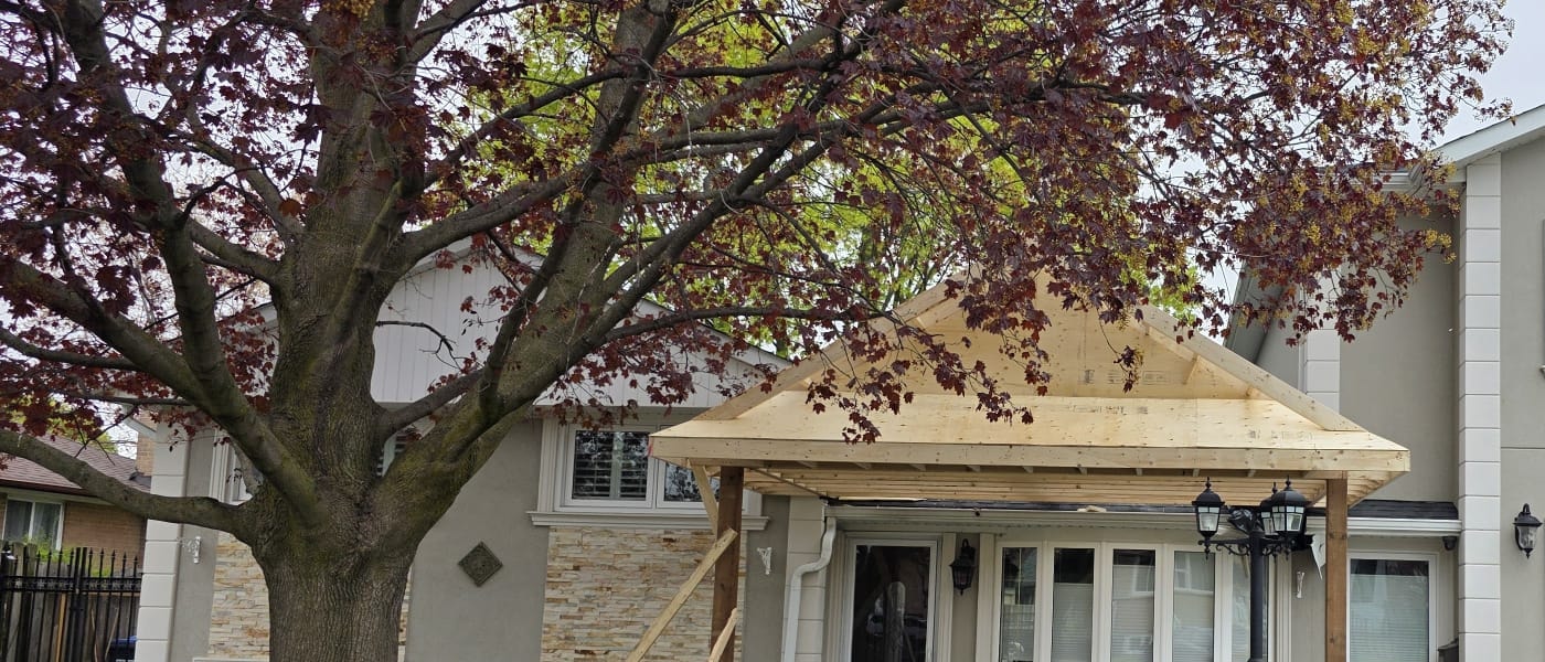 Early porch construction with wood posts, a front beam, and gable framing in place