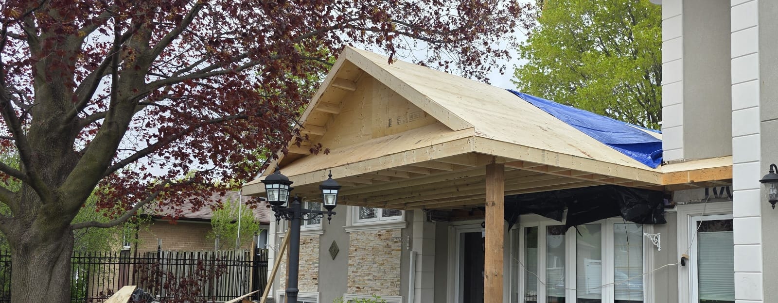 Covered porch addition with plywood roof sheathing installed over the wood frame