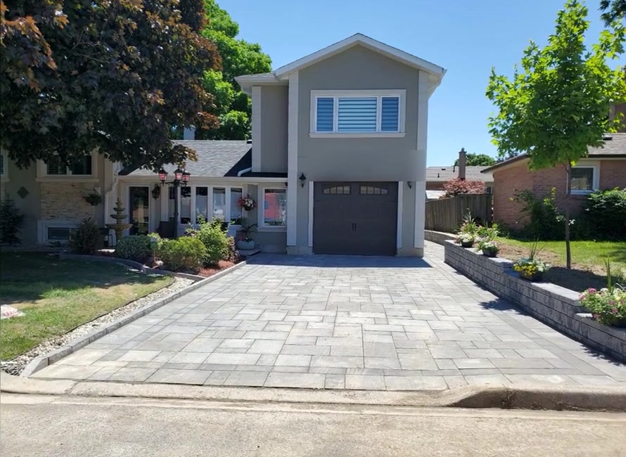 Completed attached garage addition with an upper-level window and interlock driveway